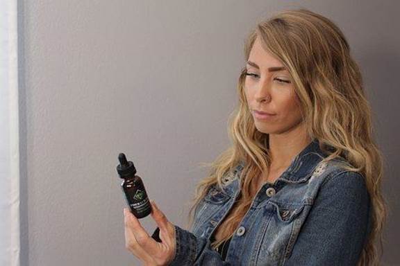 A CBD user holding a bottle of CBD oil